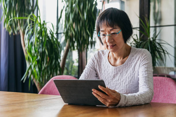 istock Senior woman wearing glasses reading digital tablet 1125619358