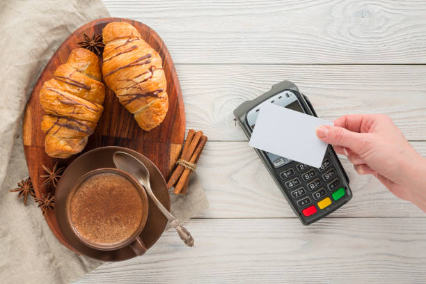 composition of coffee and croissants with bank payment terminal on a wooden background stock photo