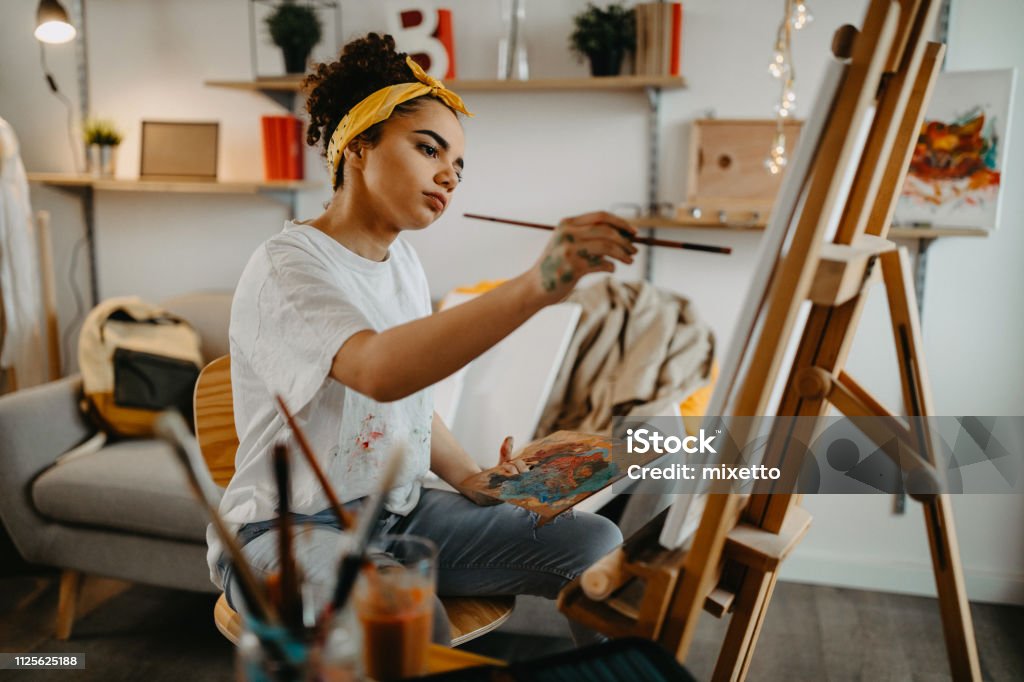 Girl painting on canvas Photo of young females artist in her apartment Painting - Activity Stock Photo