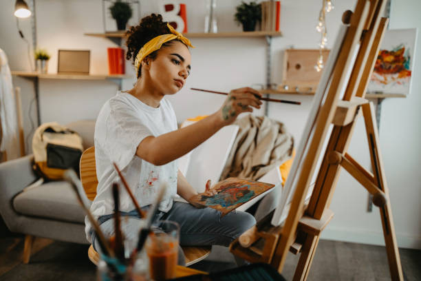 Girl painting on canvas Photo of young females artist in her apartment artist photos stock pictures, royalty-free photos & images