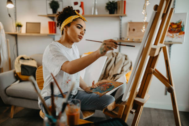 Girl painting on canvas Photo of young females artist in her apartment artists painted stock pictures, royalty-free photos & images