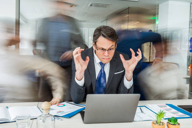 istock Angry manager using laptop among his colleagues in blurred motion. 1125629208