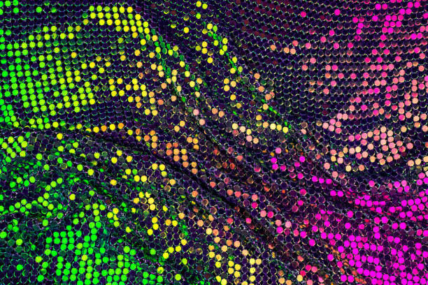 Abstract background with gold, green and purple sequins on the fabric.