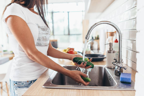 istock Woman washing cucumbers in kitchen sink close up. 1125635189