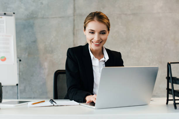 istock smiling businesswoman sitting at workplace and using laptop 1125635294