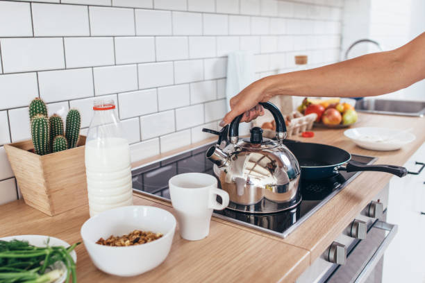 istock Woman is heating water in a kettle to make coffee. 1125635504