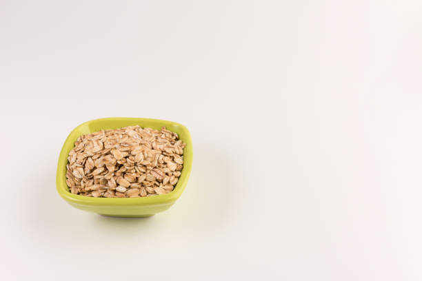 Dry rolled oatmeal in bowl isolated on white background. Top view