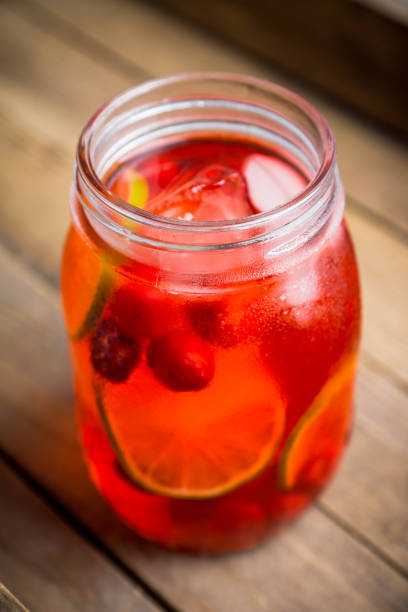 istock Red cocktail with cherry and lime in jar on the rustic background 1125637170
