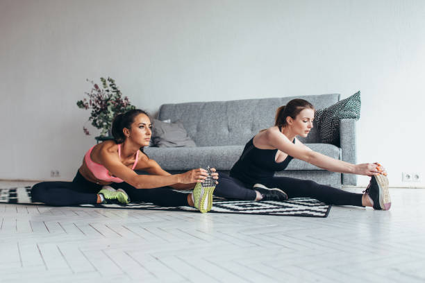 istock Fit women doing stretching while sitting on the floor at home 1125637362