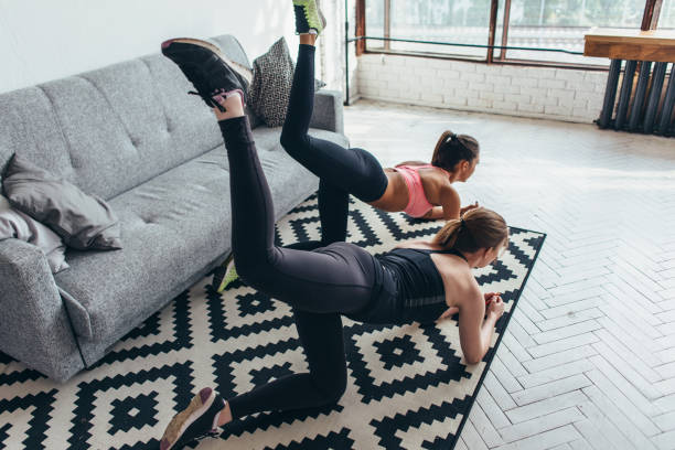 Two fit women doing bent knee donkey kick exercise in all fours position working out their buttocks at home Two fit women doing bent knee donkey kick exercise in all fours position working out their buttocks at home. ass horse family photos stock pictures, royalty-free photos & images
