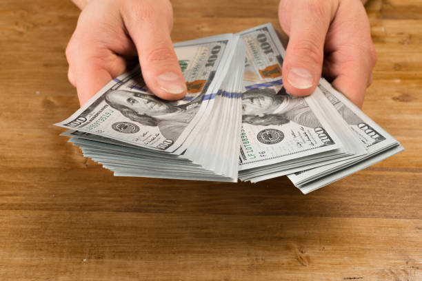 istock Man count the new us dollars on wooden table 1125637382