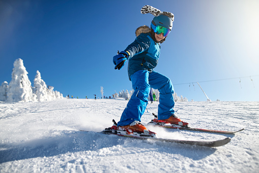Little boy skiing on a beautiful sunny winter day.  The boy is speeding on a modern wide ski slope.
Nikon D850