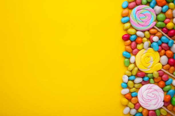 istock Colorful lollipops and different colored round candy on yellow background 1125640852