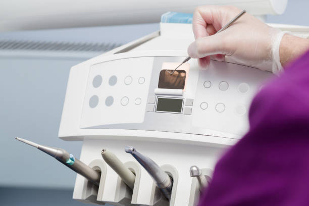 istock Dentist's hands in rubber protective gloves with tool pointing to x ray of teeth on display. Dental equipment monitor in office. Closeup. 1125646716