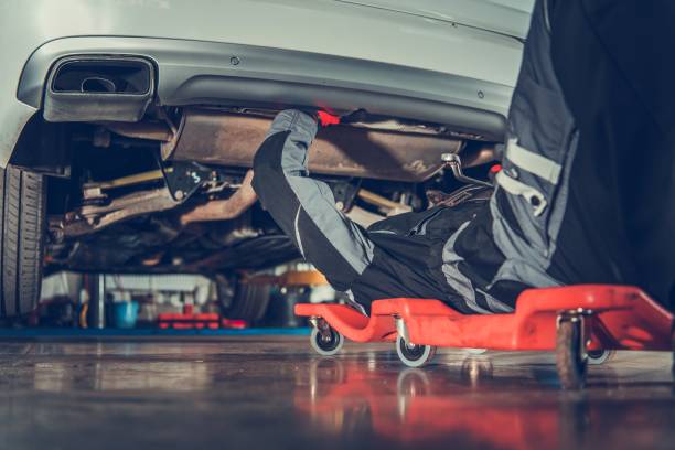Repair Vehicle From Creeper Caucasian Vehicle Mechanic in His 30s Repair Vehicle Laying Under Vehicle on the Creeper. Automotive Industry. mechanic working under car stock pictures, royalty-free photos & images