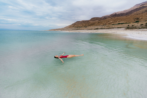 Young Caucasian woman floating on water  in Dead Sea