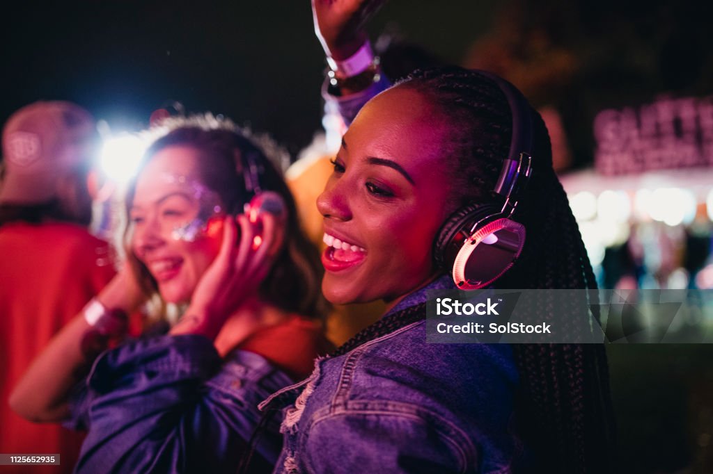 Friends Dancing in a Silent Disco Young women are having fun and dancing in a silent disco at a music festival. Nightclub Stock Photo