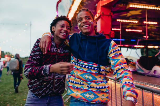 Young Couple at a Funfair Young couple are laughing and talking as they walk around a funfair. teens interacting photos stock pictures, royalty-free photos & images