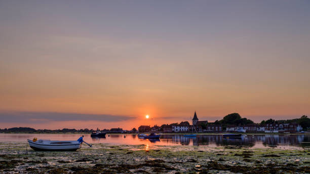 pôr do sol de verão sobre o porto de bosham e vila com igreja torre de igreja da santíssima trindade, west sussex, reino unido - chichester england - fotografias e filmes do acervo