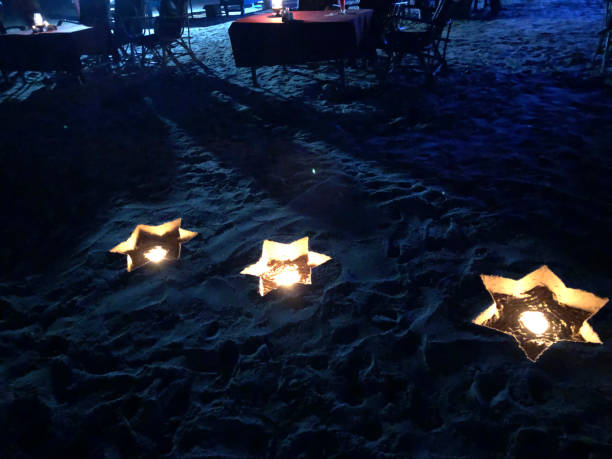 Goan beachfront restaurant illuminated at night by candles in star-shaped holders made by digging holes in the sand of Palolem Beach.