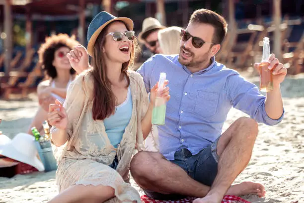 Happy young couple enjoying picnic on the beach and have good time on summer vacations.