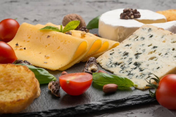 istock Different kinds of cheeses on a black board, with cherry tomatoes and basil and nuts. 1125657140