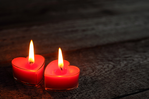 Heart shaped candles burning on wooden background, Valentines day concept