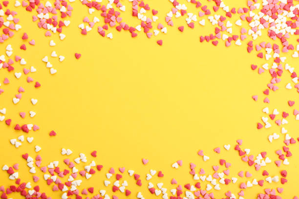 istock Colorful heart shaped sprinkles on yellow background 1125662080