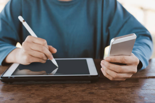 istock Hand holding smartphone and pen on tablet for business 1125662488