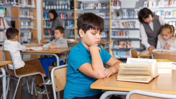 istock Tween boy reading textbooks in school library 1125668680