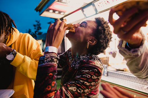 A young women enjoying pizza with friends at a music festival.