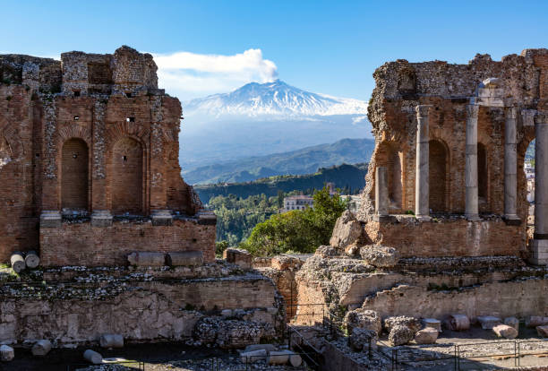 Volcano Etna in Sicily seen through ruins of ancient amphitheater in Taormina Two Sicilian landmarks on one photo sicily photos stock pictures, royalty-free photos & images