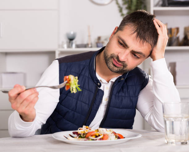 istock Man looking at  vegetable salad before eating  indoors 1125674335