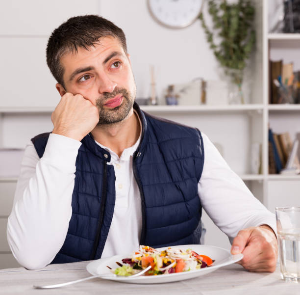 istock Sadly young man before eating vegetable salad from plato 1125674339