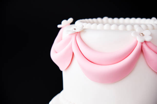 istock White wedding cake with pink elements made from pastry mastic on a black background. 1125674921