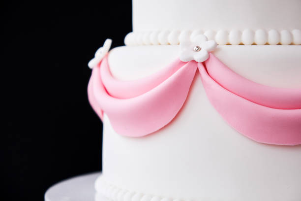 istock White wedding cake with pink elements made from pastry mastic on a black background. 1125674963