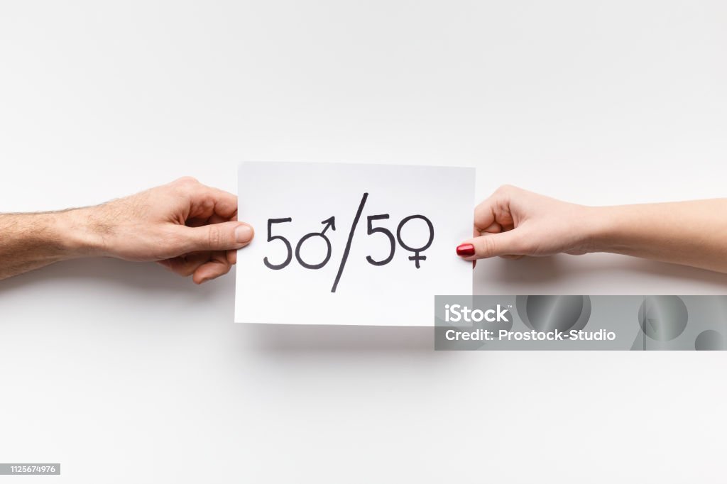 Text 50/50 written on piece of paper Gender parity. Man and woman holding paper with text 50/50, zeros as female and male symbols, copy space Equality Stock Photo