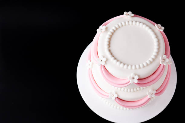 istock White wedding cake with pink elements made from pastry mastic on a black background. 1125675039