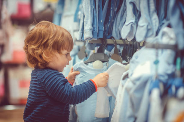 istock Cute little boy choosing blue clothes during shopping 1125678379