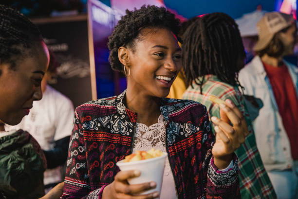 Friends Having Food at a Festival Small group of friends are sharing portions of chips at a festival. food festival stock pictures, royalty-free photos & images