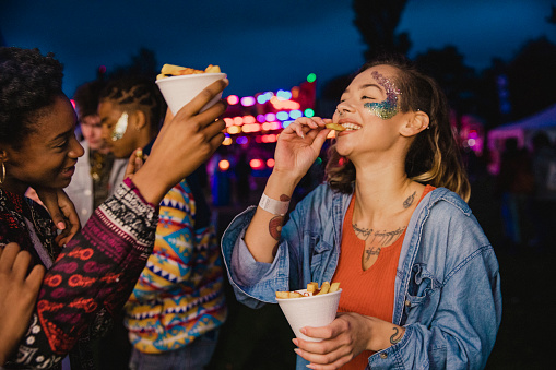 Small group of friends are sharing portions of chips at a festival.