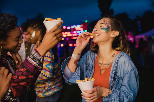 Sharing Chips at a Festival Small group of friends are sharing portions of chips at a festival. food festival stock pictures, royalty-free photos & images