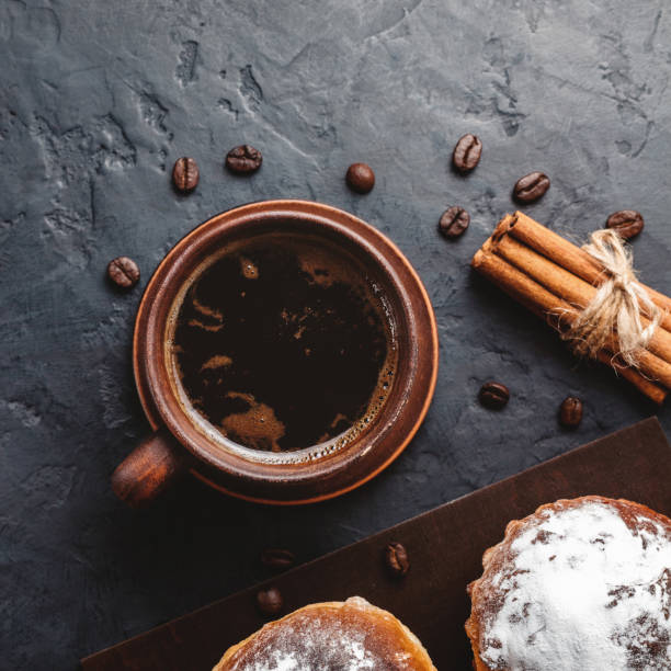 istock Cup with hot coffee, muffins and cinnamon sticks on the dark, textured background, top view 1125679951