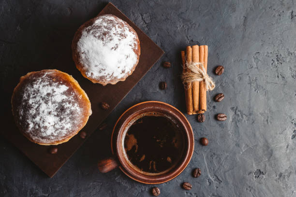 istock Cup with hot coffee, muffins and cinnamon sticks on the dark, textured background, top view 1125679956