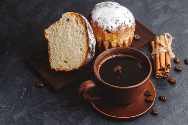 istock Cup with hot coffee, muffins and cinnamon sticks on the dark, textured background 1125680078