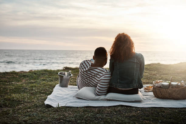 The perfect end to a perfect date Shot of a young couple watching the sunset on a romantic date outdoors black couple sunset stock pictures, royalty-free photos & images