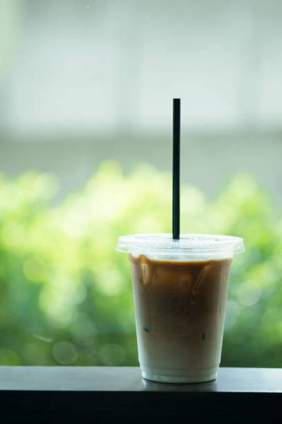 Take away cup with iced latte on green nature background