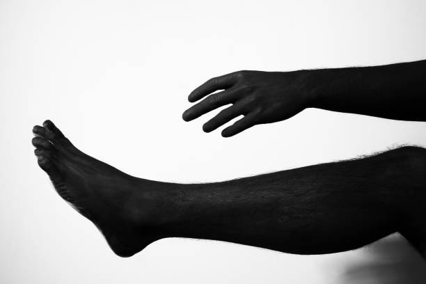 Black hand and leg reach our each other on white background