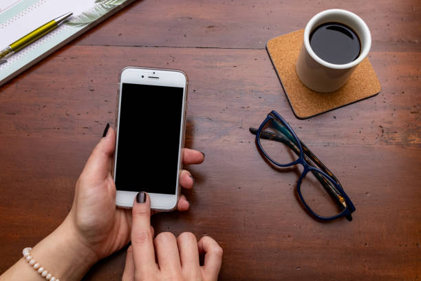 istock Woman hand holding smartphone on wooden desk while taking a break 1125690711