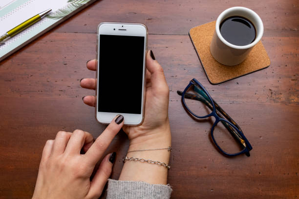 istock Woman hand holding smartphone on wooden desk while taking a break 1125690717